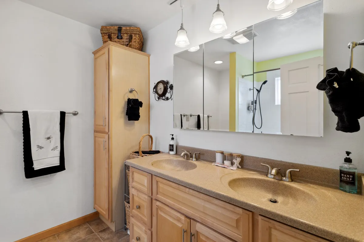 A bright, modern full bathroom equipped with double sinks, large mirrors, abundant storage, and a shower area. The space feels organized and calming, ideal for morning routines or unwinding in the evening.