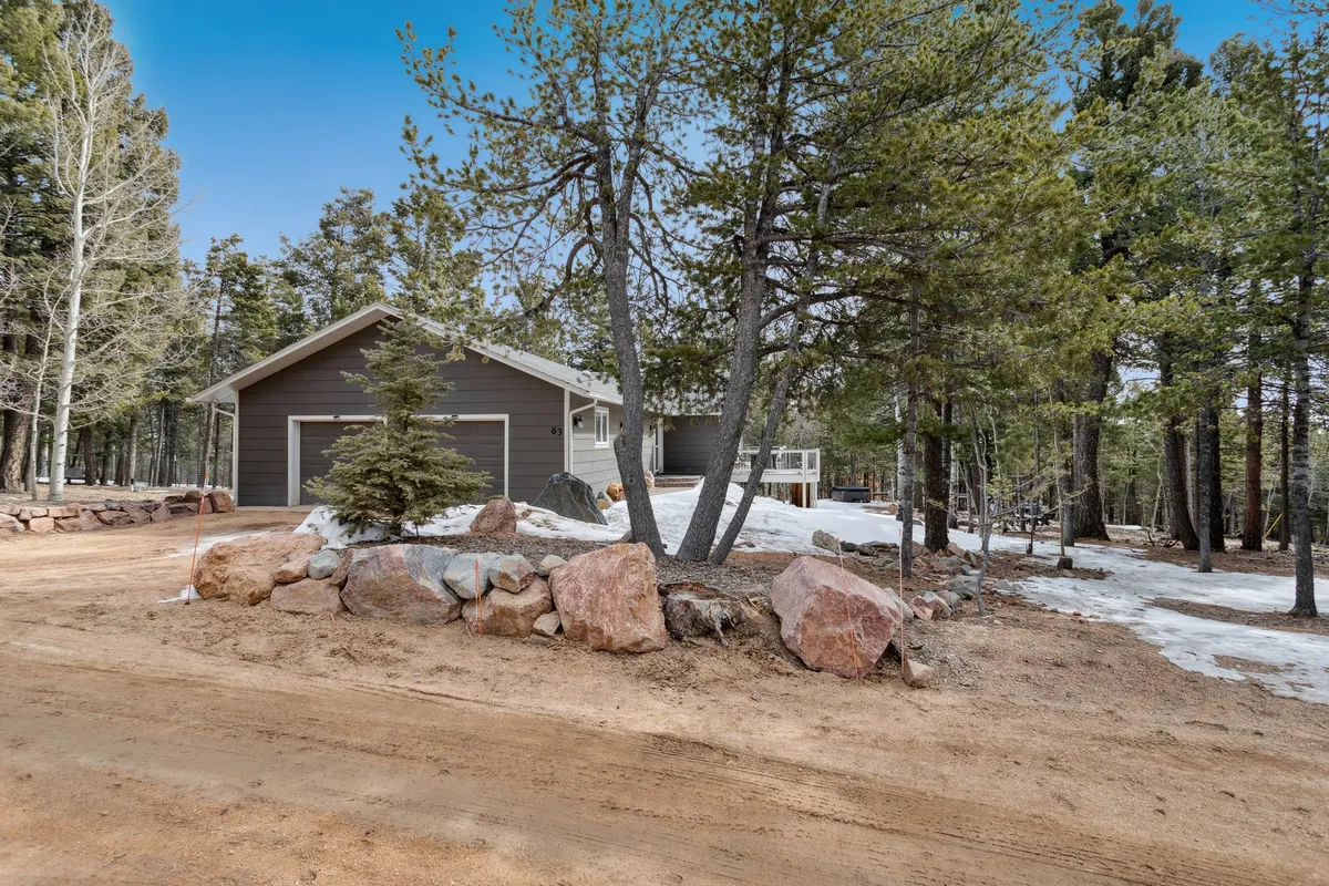 Featuring a modern house nestled among tall pine trees and dramatic rock formations, this scene emphasizes the property's direct connection to the natural landscape and hints at hiking opportunities right from the doorstep.