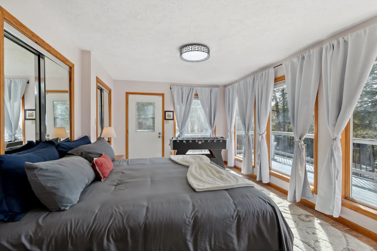 An interior image showing a cozy king-sized bed positioned near large windows, with a foosball table adjacent. The scene suggests both relaxation and playful activities, encapsulating the warmth and fun of shared moments in a family-friendly setting.